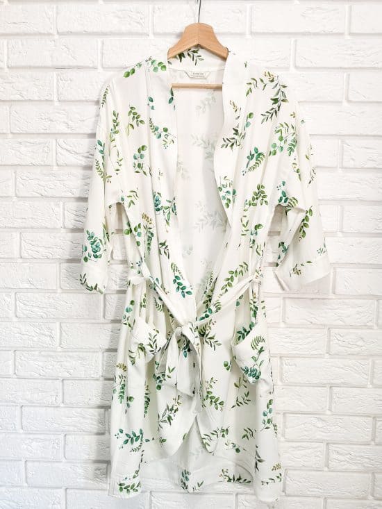 white bathrobe hanging on the white wall with bricks with leaves watercolor pattern design