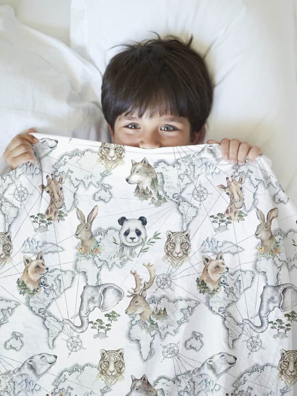 boy presenting kids bedding with seamless pattern with the world map and animals motif