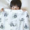 boy presenting bedding for kids with seamless pattern with panda bears